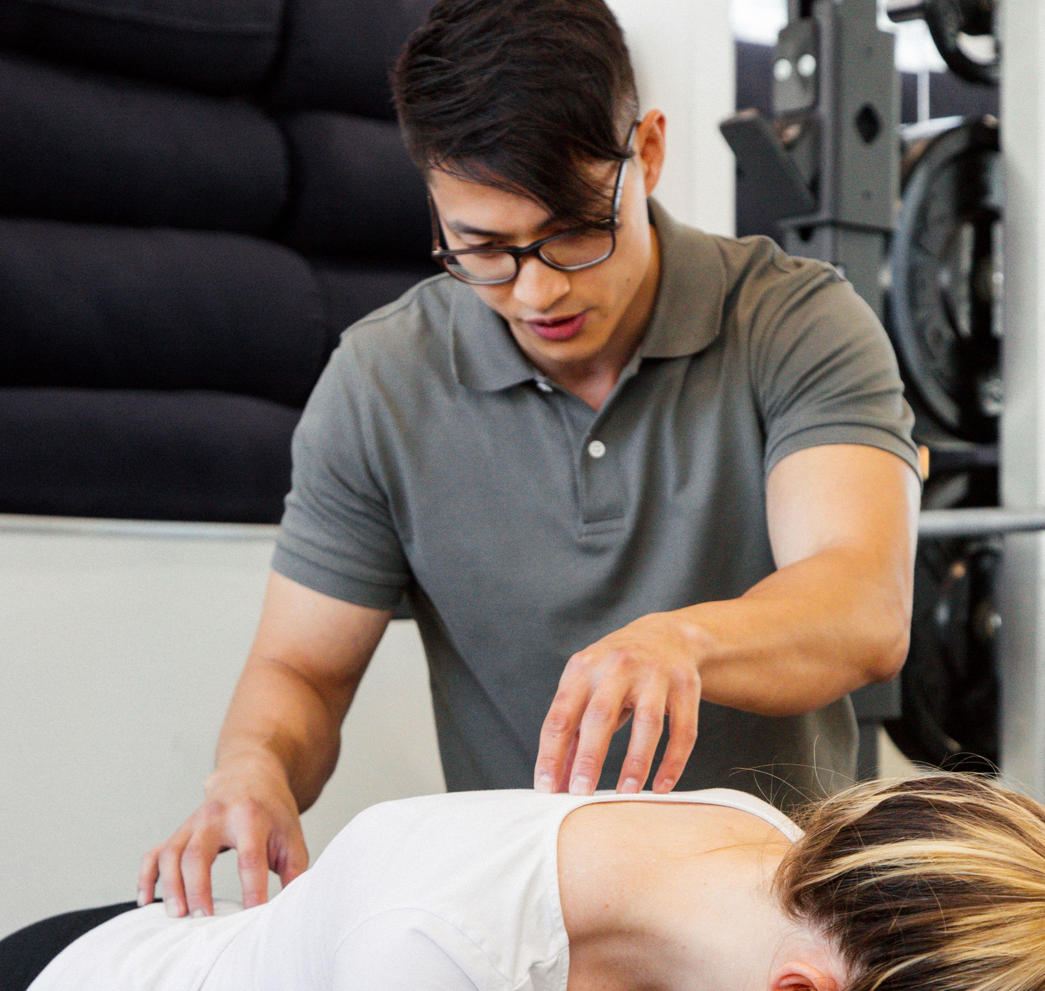 Dr. Frank Nhan guiding a patient through the cat cow exercise in the clinic.
