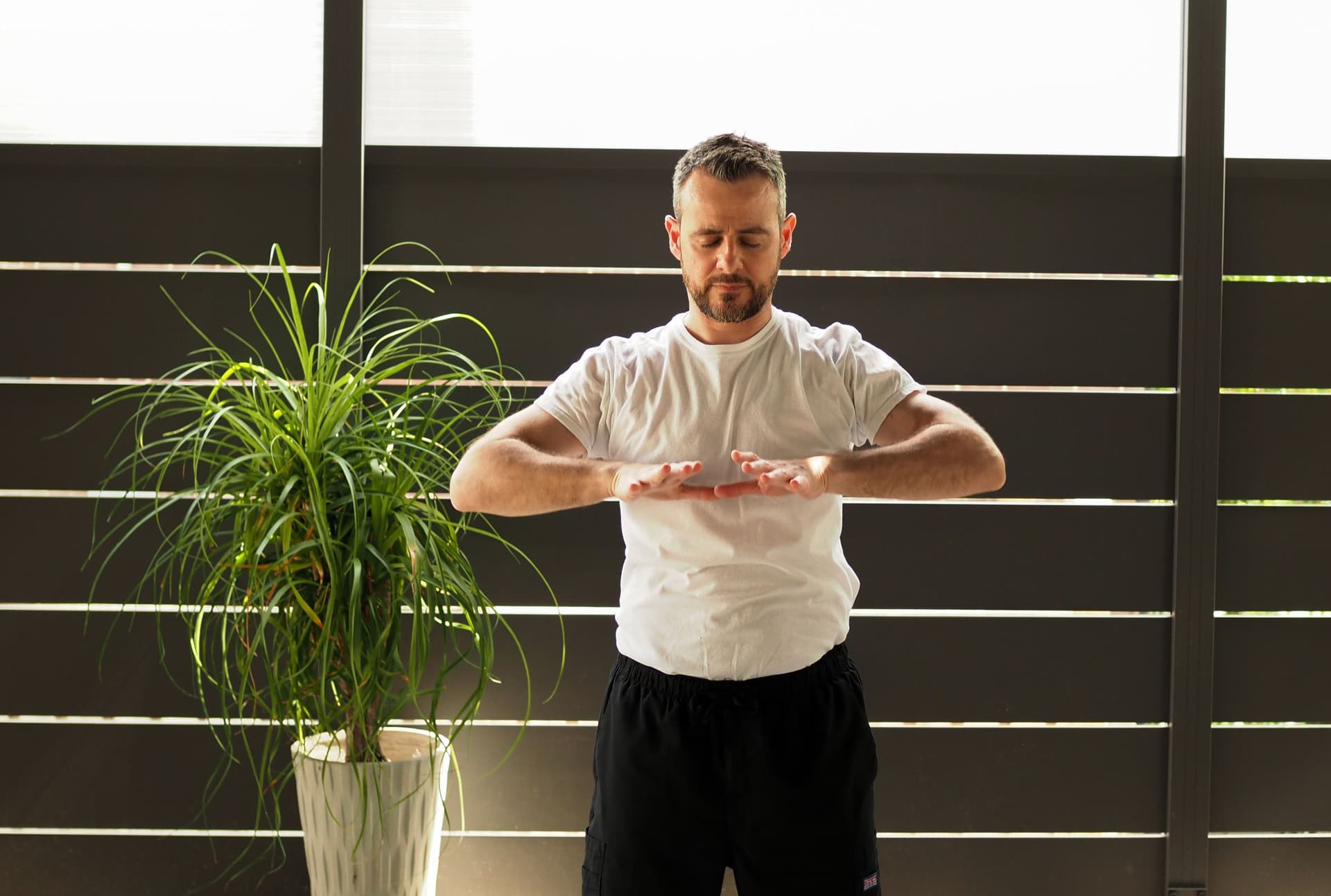 A photo of a person with arms in a rectangular formation, meditating, and performing Tai chi.