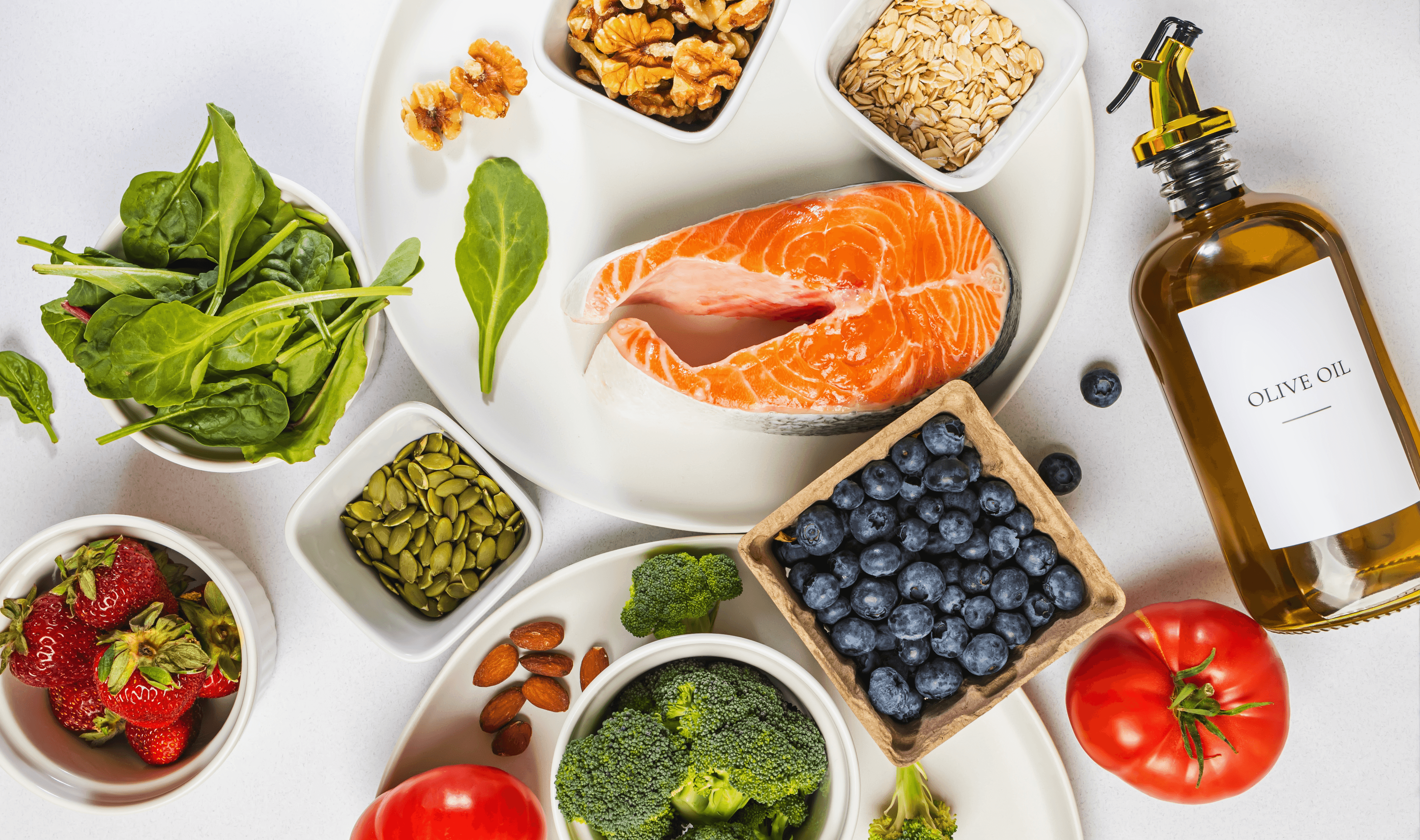 Apricots scattered on white surface with bowl, cutting board, and flowering branch.