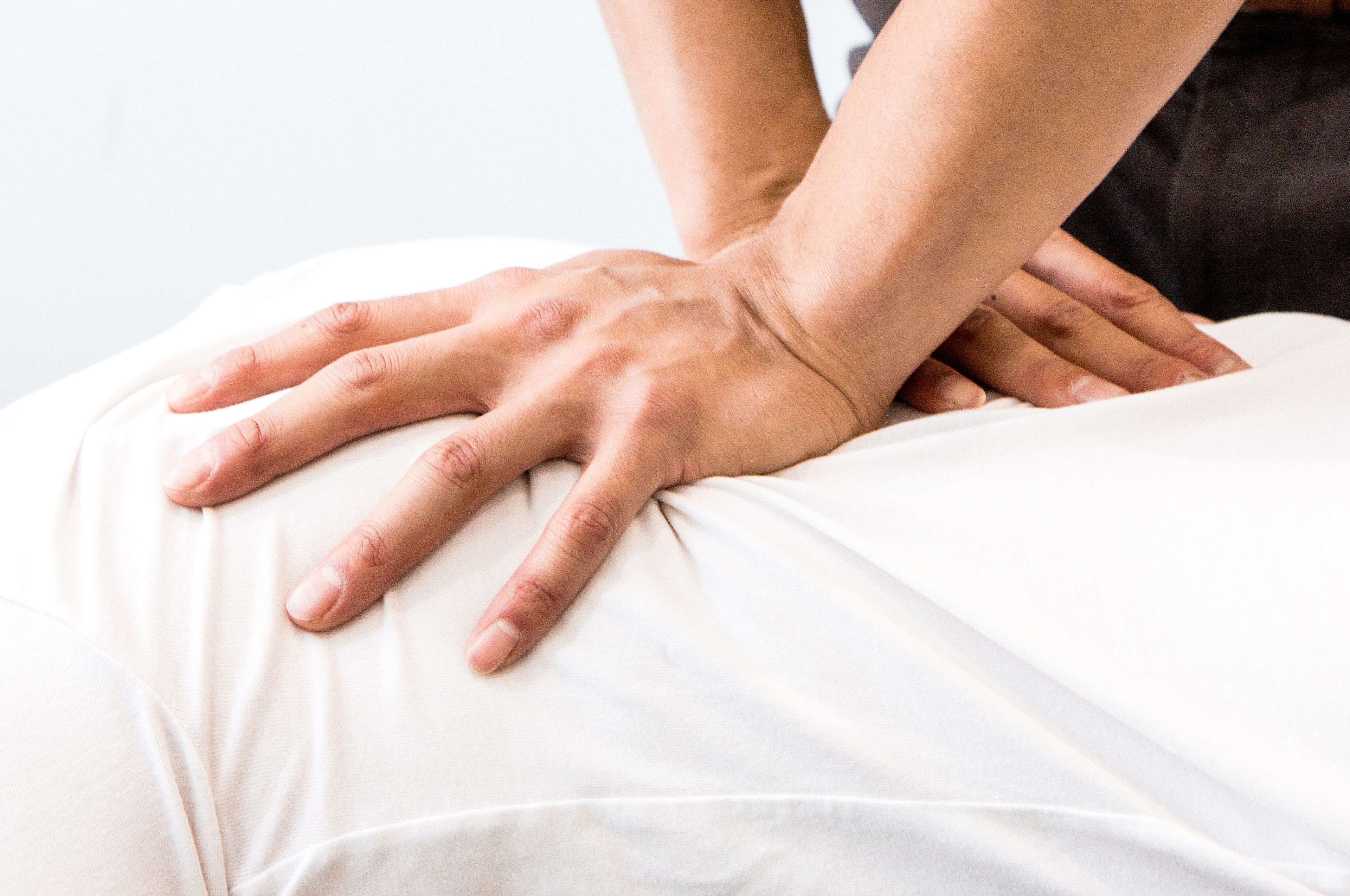 A photo showing hands performing a chiropractic or massage technique on a person's back.