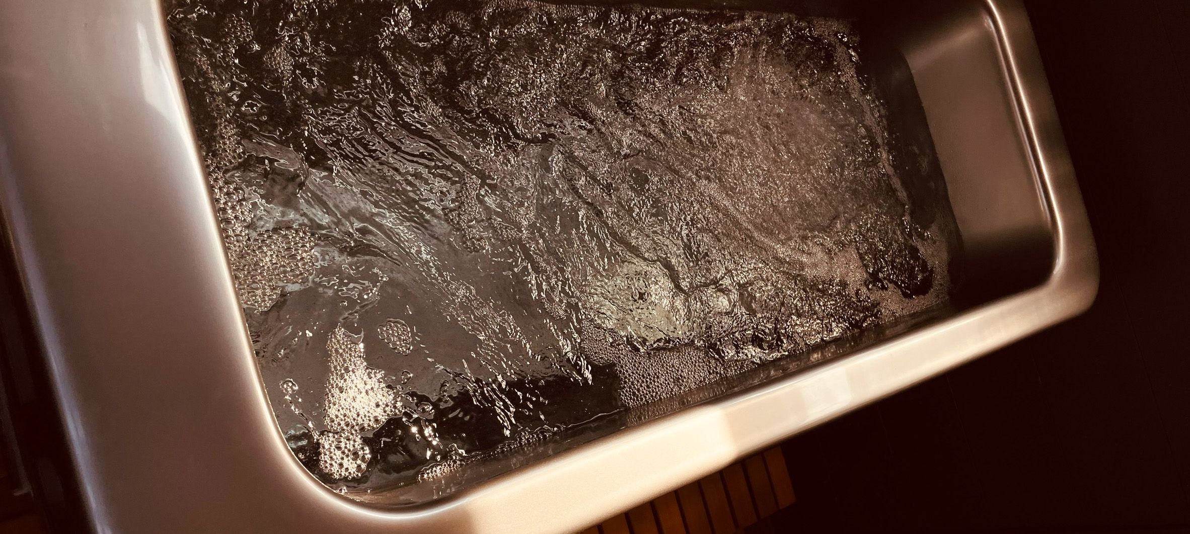 A serene, close-up, photo positioned horizontally of a bath bubbling with water.