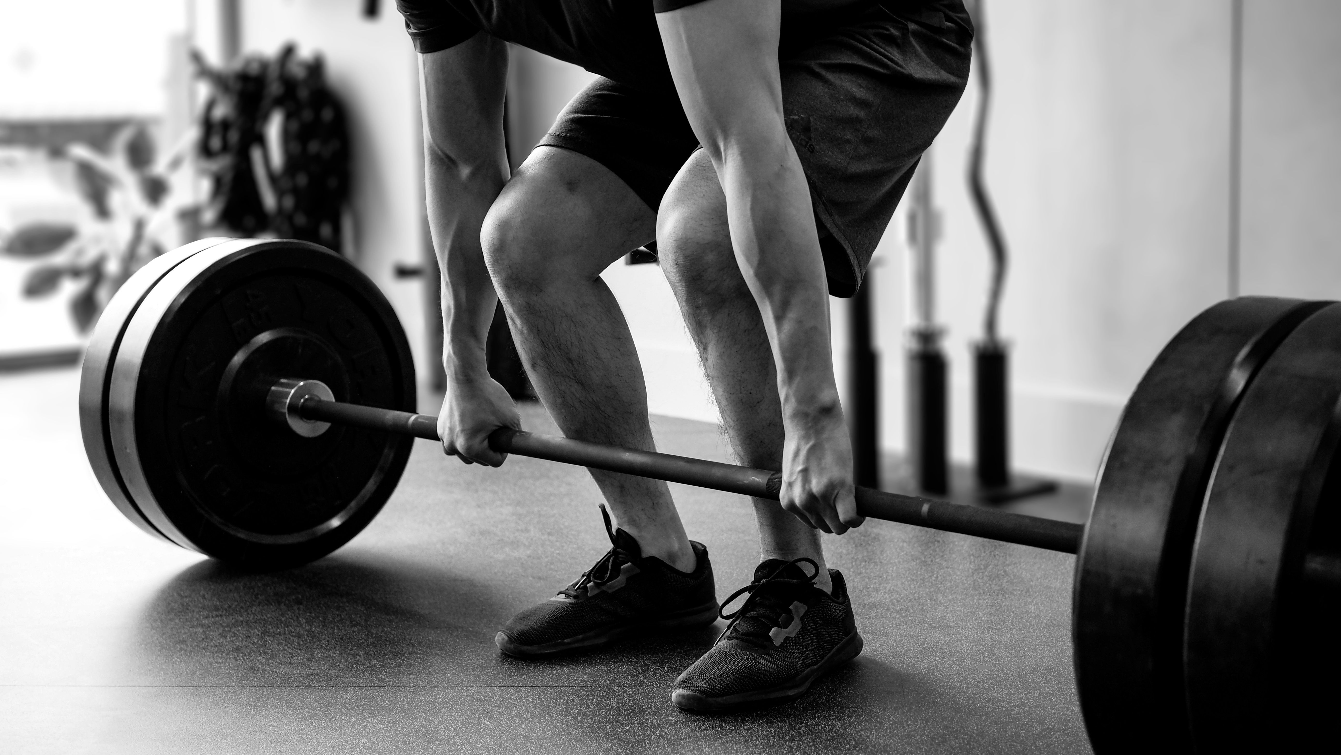 Black-and-white photo of a man lifting a giant weight with both arms.