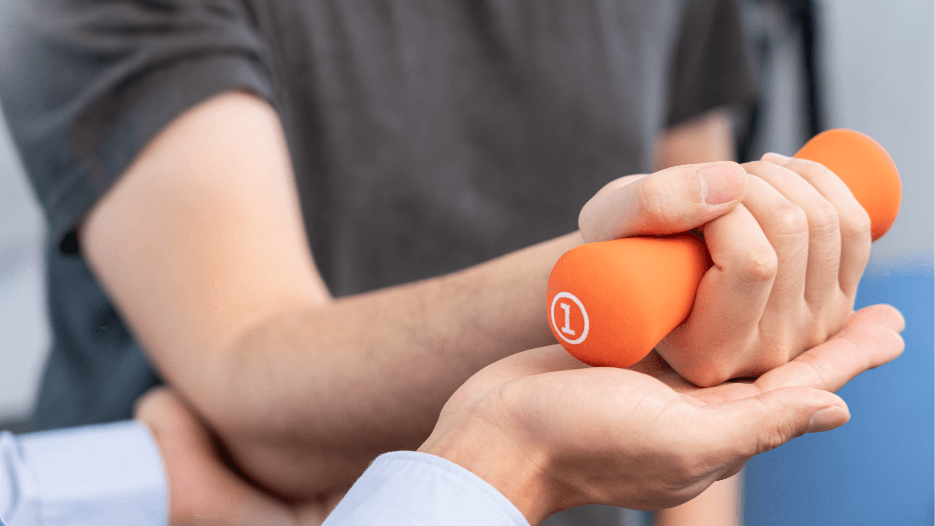 A photo showing a physical therapy session, with a person holding an orange hand weight guided by another's hand.