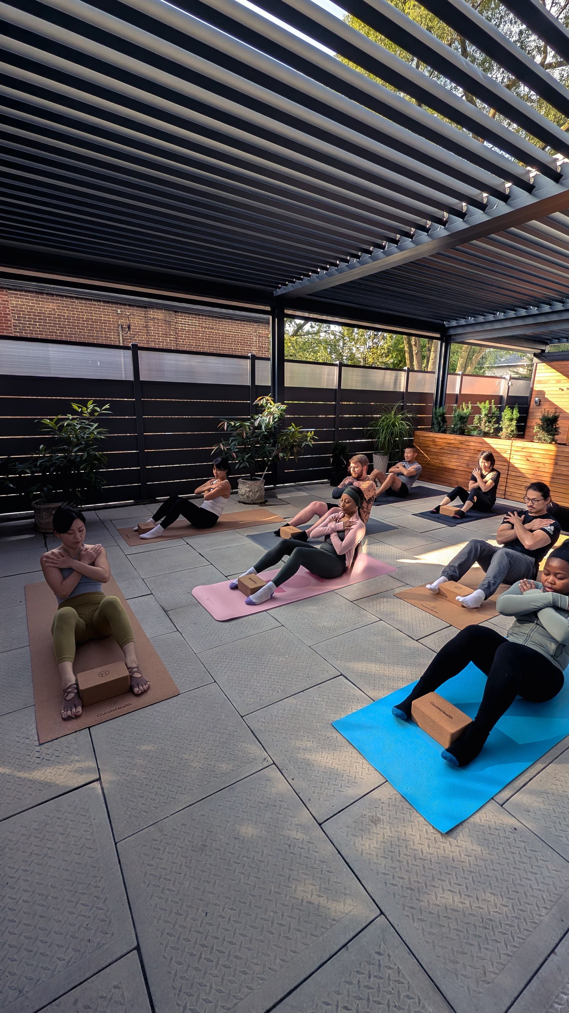 Photograph of a group of people doing yoga on mats with their arms crossed leaning back.