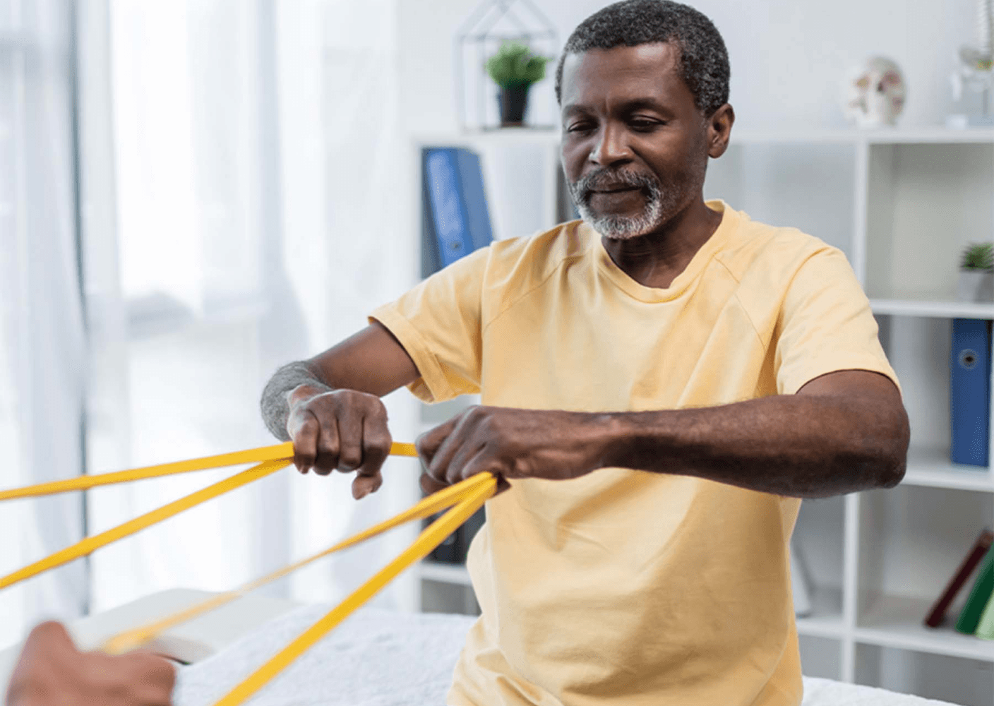 Photo of an older man performing resistance band exercises in a therapy session, focusing on strength and mobility improvement.